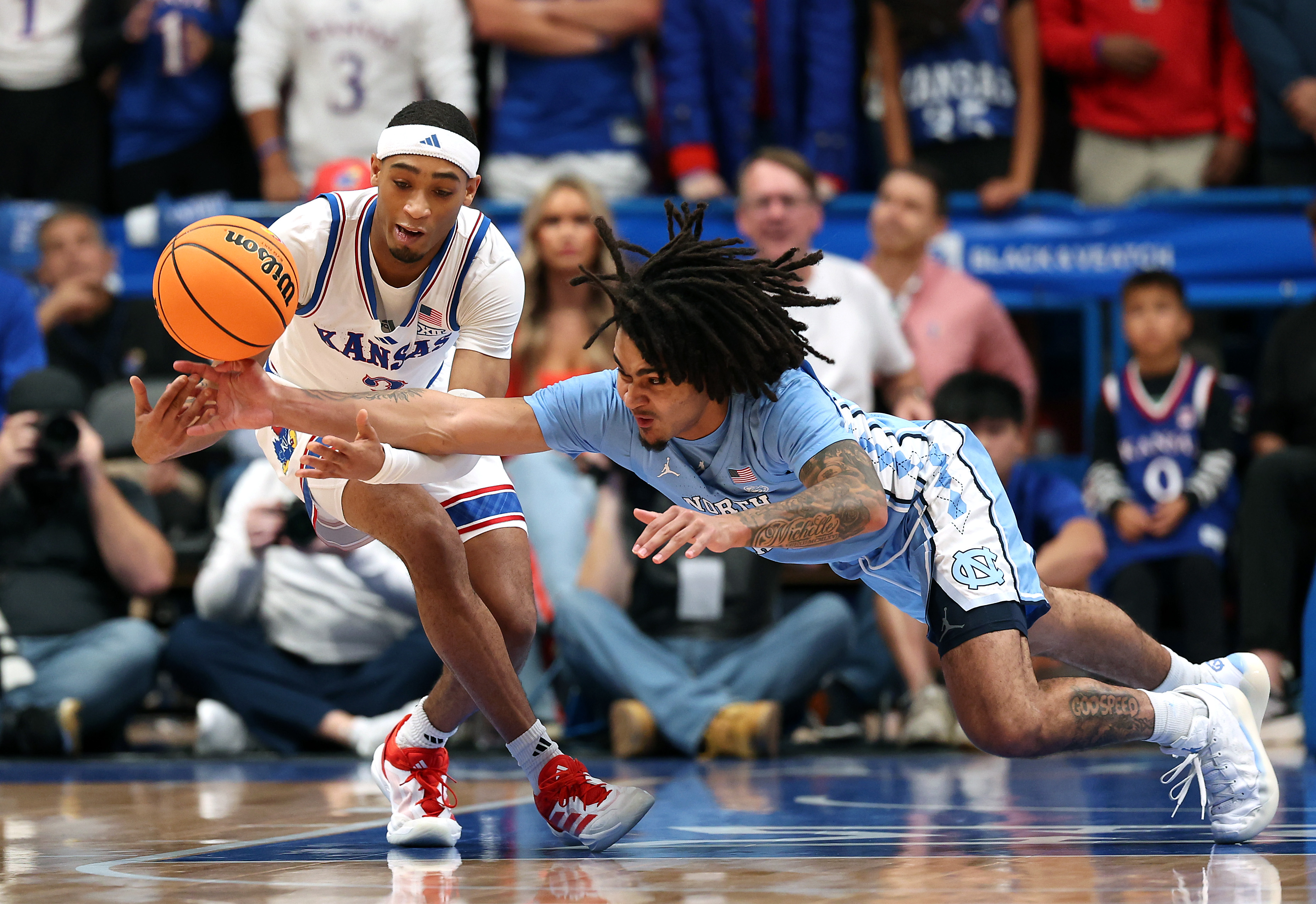 Dajuan Harris Jr. #3 of the Kansas Jayhawks and Elliot Cadeau #3 of the North Carolina Tar Heels battle for a loose ball during the first half of the game at Allen Fieldhouse on November 08, 2024 in Lawrence, Kansas.