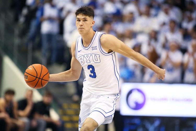 BYU guard Egor Demin holds the ball in one hand about to throw a pass during a game.