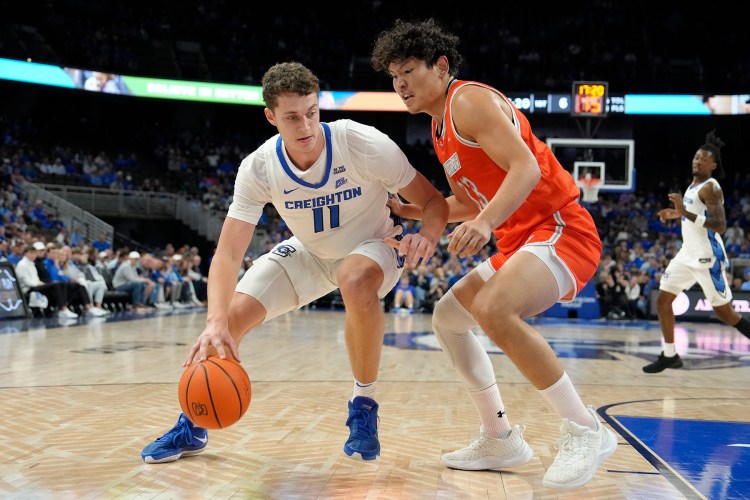 Creighton center Ryan Kalkbrenner dribbles the ball while being defended closely just outside the paint.