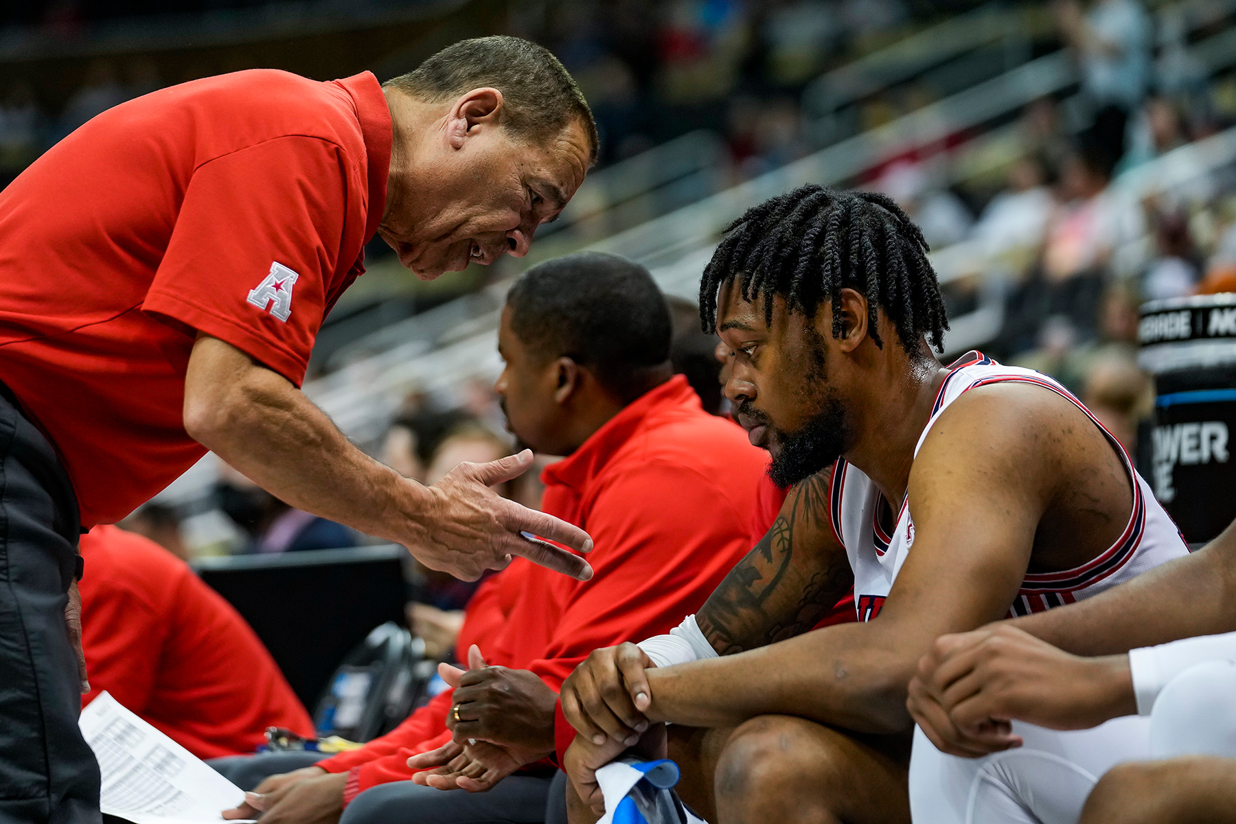 During a game, Houston coach Kelvin Sampson talks to J'Wan Roberts, who is sitting on the bench