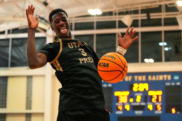 AJ Dybantsa with his tongue out and his hands open after completing a dunk in a game.