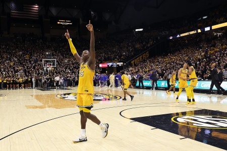 Missouri forward Mark Mitchell stands on the court with his arms in the air, celebrating a win over Kansas.